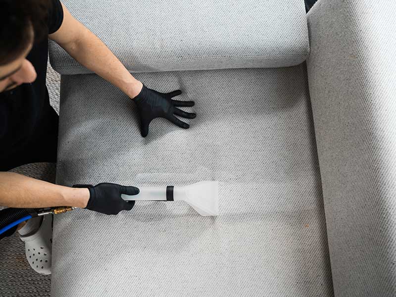 Professionele proefreiniging van stoffen bank Vakman reinigt een lichte stoffen bank met een professionele extractor